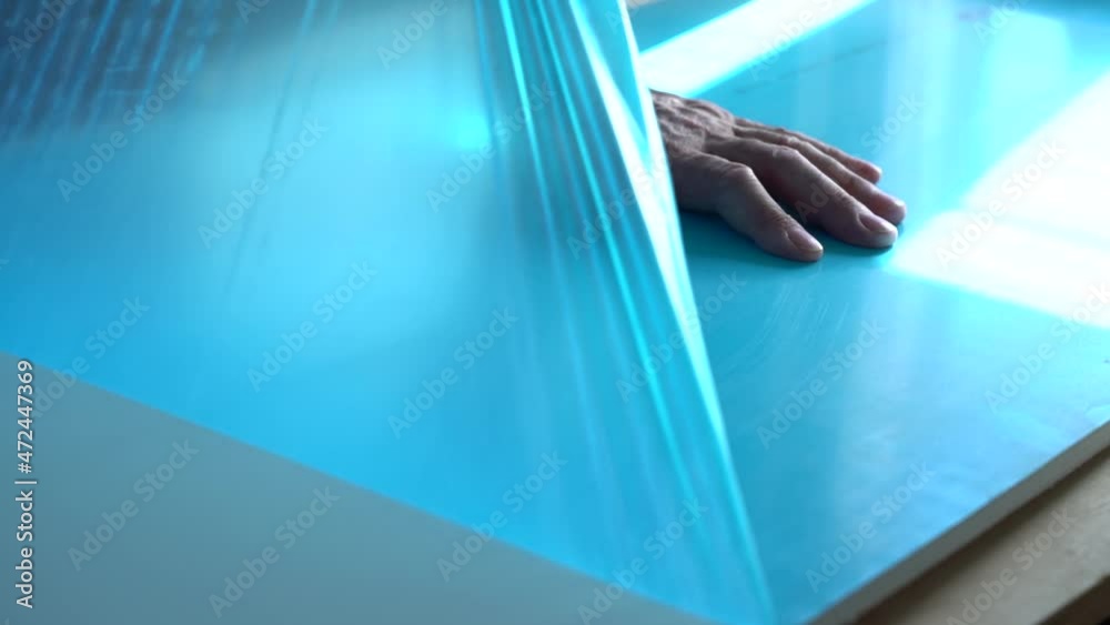 Worker's hands remove the protective film coating