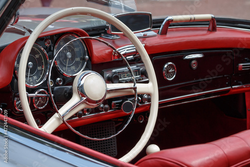 Oldtimer mit rotem Leder Innenraum und weißem Lenkrad mit Radio und Tacho Armaturen © Bigwuschel