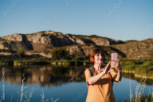 Wallpaper Mural Senior woman taking selfie through smart phone near lake Torontodigital.ca