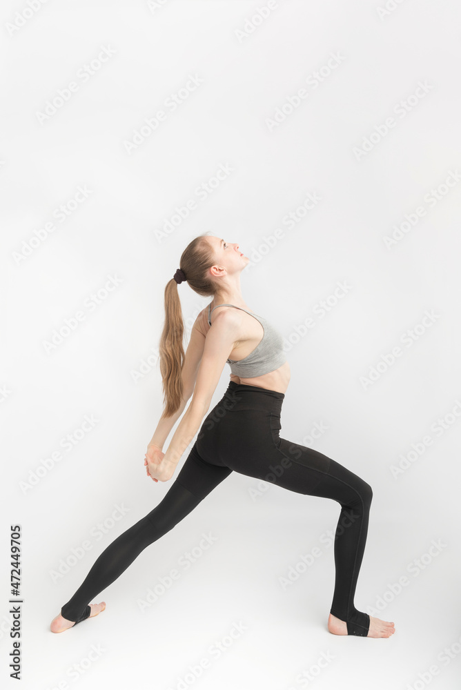 Young woman with sports figure is engaged in yoga. Yoga instructor side view on white background.