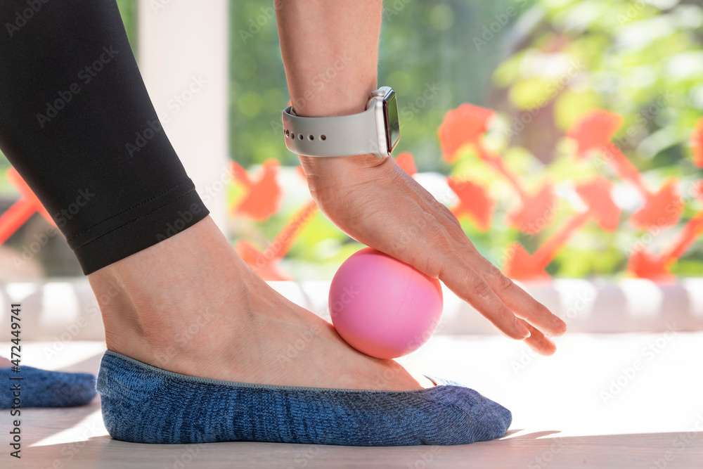 Girl using massage tool for foot massage. Exercise equipment for self-masage. Myofascial ball. Close up