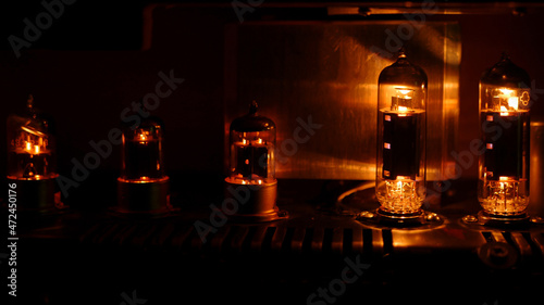 Close up silhouette of eletronic vacuum radio tube. Old analog electronic audio components glowing orange.