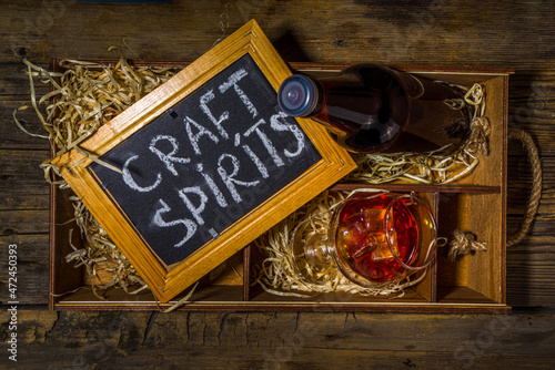 Craft spirit alcohol. Various bottles and glass with hand crafted hard strong alcohol drinks. Old wooden rustic background copy space