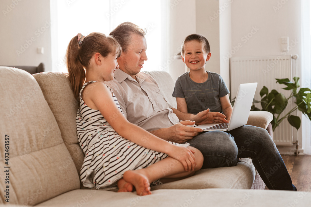 Vido call. Dad and children sit on the couch and call online grandparents or mom. Communication online, at a distance using the Internet.