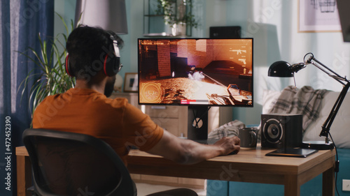 Canvas Print Side view of bearded Indian man in casual clothes and wireless headphones sittin