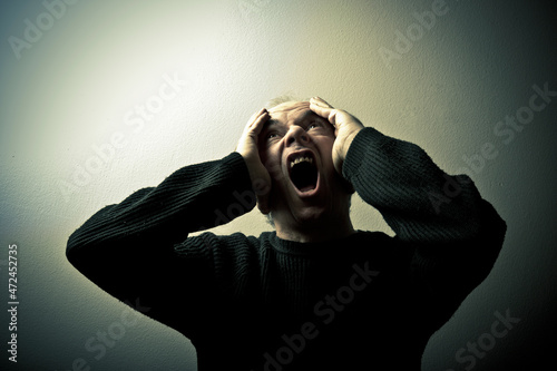 man with hands on his head screaming, concept for madness and insanity