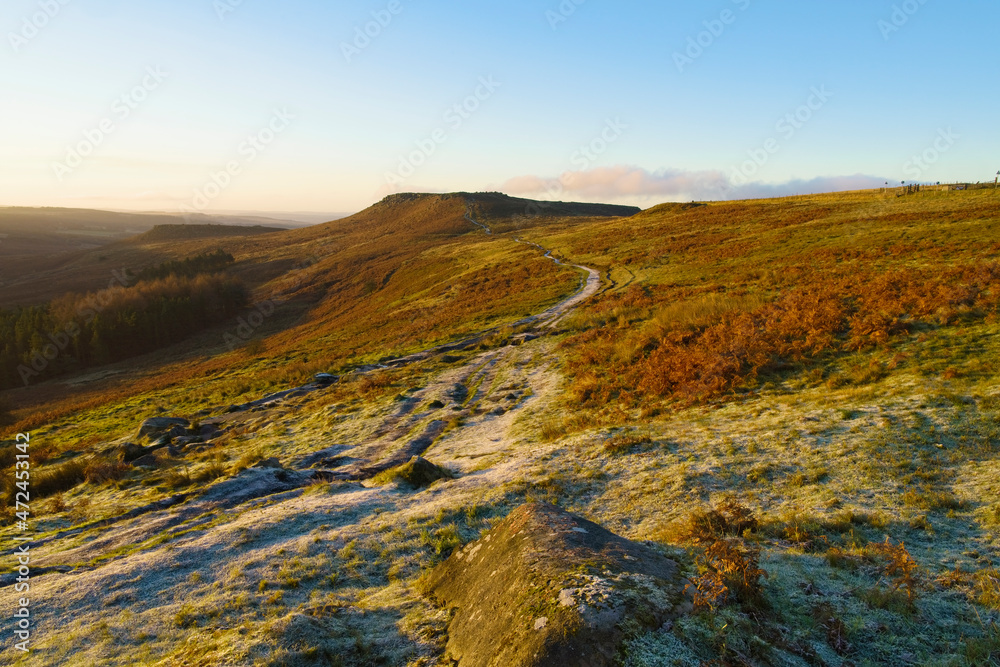 Frosty footpath extends across the slopes of Burbage Valley towards Higger Tor in the Derbyshire Peak District.