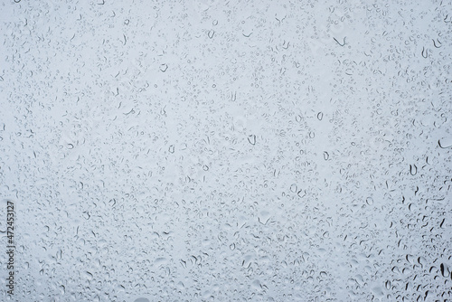 Closeup of rain drops on window on grey sky background
