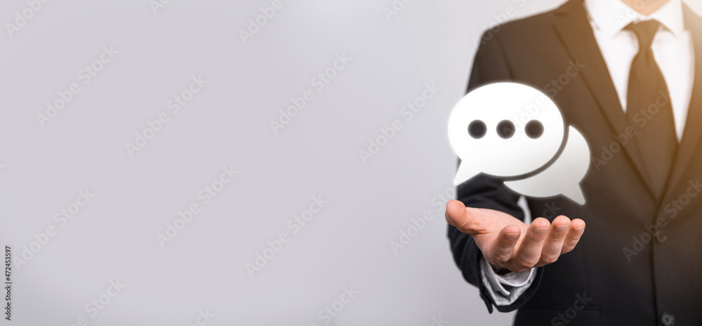 Businessman holding a message icon, bubble talk notification sign in his hands. Chat icon, sms icon, comments icon, speech bubbles Businessman holding a message icon, bubble talk notification sign in his hands. Chat icon, sms icon, comments icon, speech bubbles