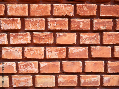 Fragment of a red brick wall. Narrow brickwork. Bright background.