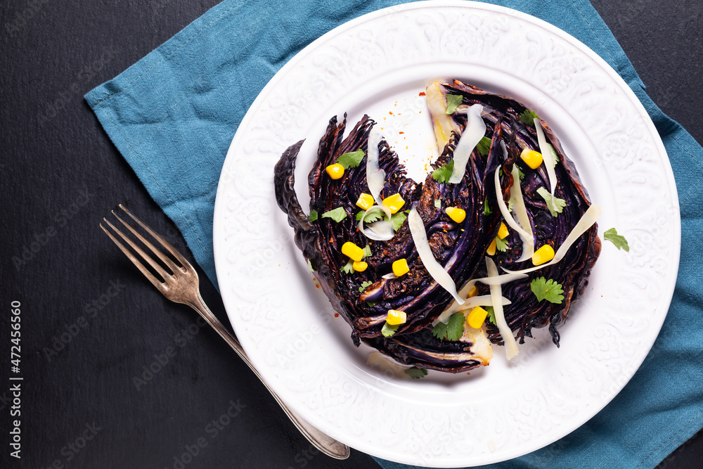 Healthy food concept vegetarian Roasted red cabbage steak on white ceramic plate on black slate stone board with copy space Healthy food concept vegetarian Roasted red cabbage steak on white ceramic plate on black slate stone board with copy space