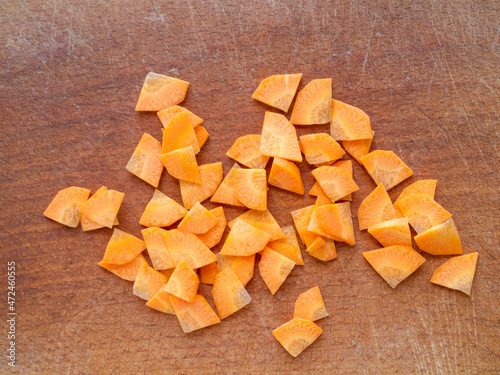 Closeup of chopped carrots on a wooden board. Paysanne cut.
