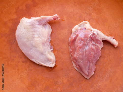 Top view of quail supreme breast on a brown clay plate. Fresh raw meat.