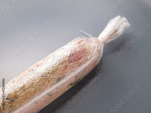 Side view of minced meat wrapped in cling film. Butter and spices are added inside. A budget homemade alternative to the sous vide technique.