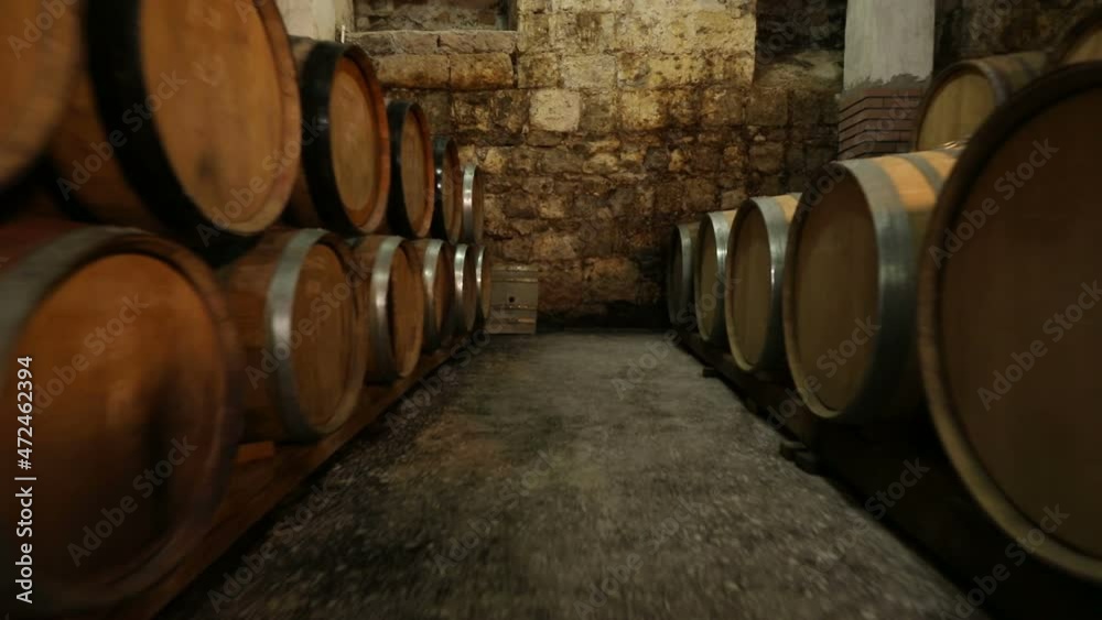 A Wine Cellar. Storage Room for Wine in Bottles and Barrels. Old wine in a dark underground vault. Wooden oak whiskey, wine, cognac, brandy or beer barrels. Bottles on wooden shelves. A Wine Cellar. Storage Room for Wine in Bottles and Barrels. Old wine in a dark underground vault. Wooden oak whiskey, wine, cognac, brandy or beer barrels. Bottles on wooden shelves.
