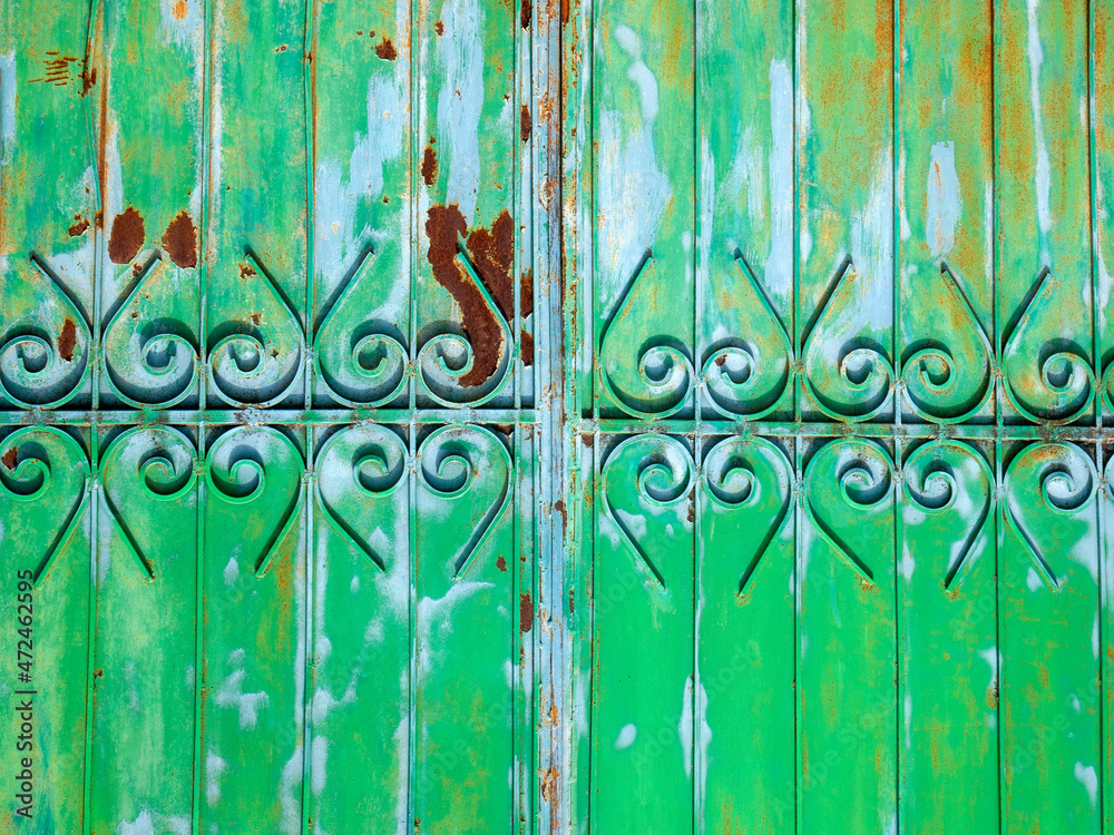 Fototapeta premium Part of a metallic green and blue fence. Colorful stains of paint and rust on the surface.