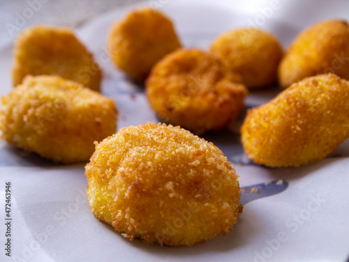 Side view of cheese croquettes on white paper. Delicious appetizer.