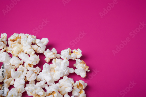 Heap of popcorn on bright pink background. Top view, copy space.