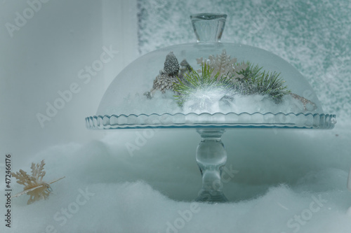 Transparent glass dish with pine branches, cones in artificial snow. Beautiful Merry Christmas decorative elements, snowy background photo