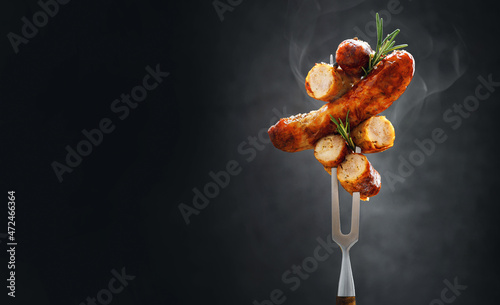 a whole and sliced grilled hot fried sausage is strung on a meat fork