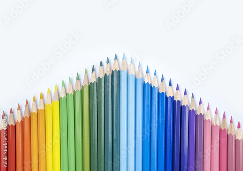 Closeup of colored pencils lined up in a row and abstract shape on background copy space