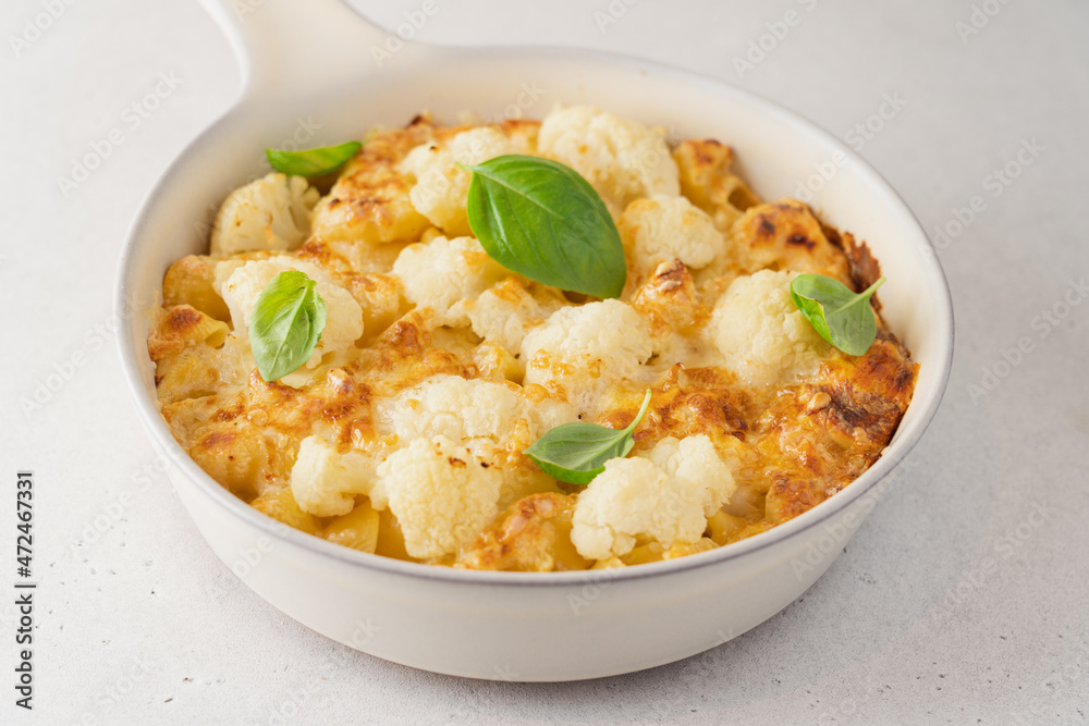 Mac and cheese with cauliflower. Baked pasta with cheese and cabbage in ceramic pot on white background. American cuisine concept