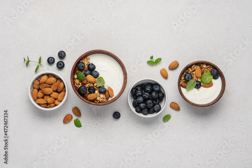 Homemade granola with berries and yoghurt. Bowl of Greek yogurt with almond nuts, oat granola and fresh blueberries on white background