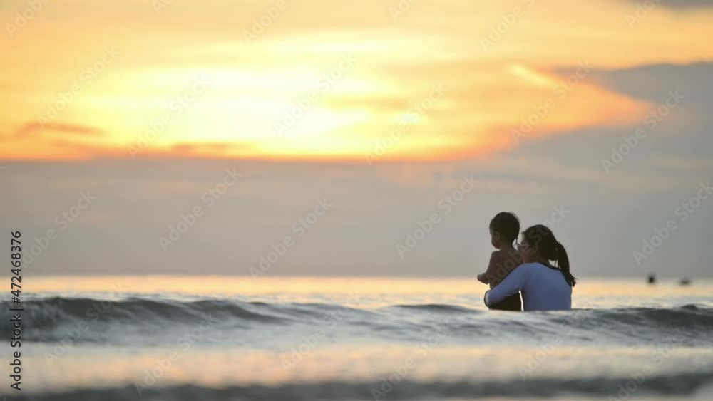 Happy family resting at beach in summer, Mother and baby boy feet at the sea foam at the sunlight water is moving Happy family resting at beach in summer, Mother and baby boy feet at the sea foam at the sunlight water is moving