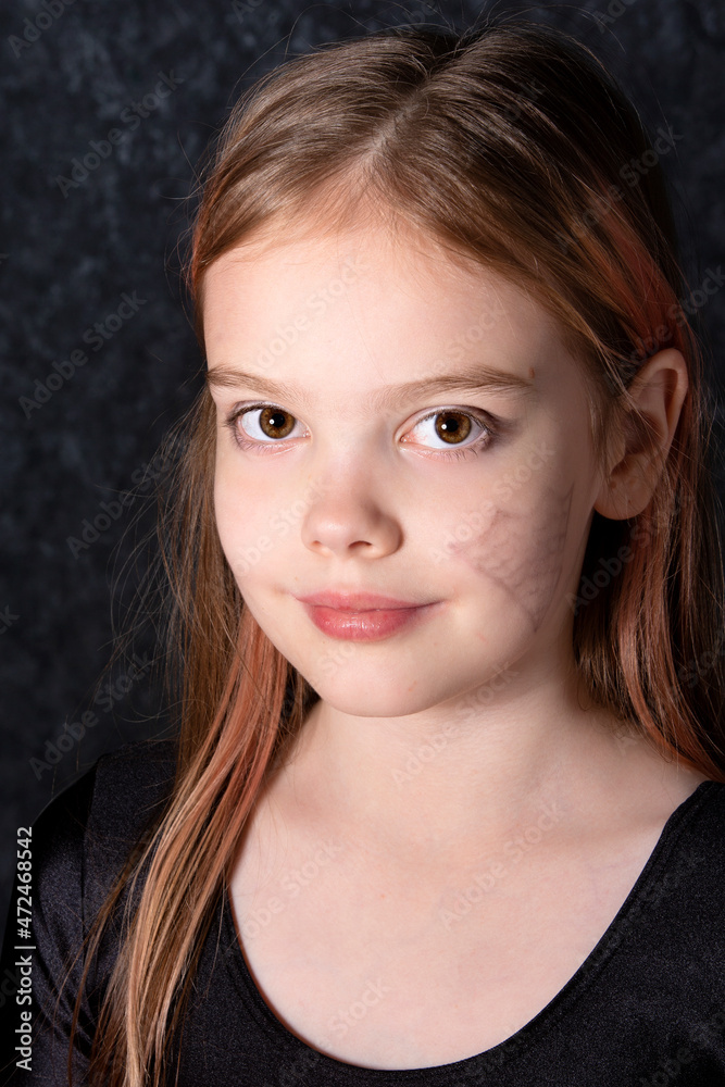 Portrait of a little girl with a spider web drawing on her face.