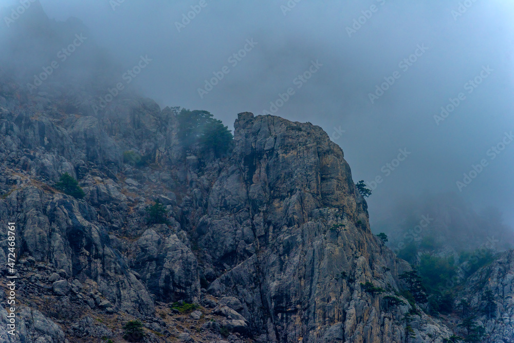 Stony slopes of mountain in dense fog.