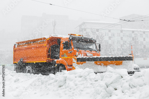 A large orange snowplow stands on the road before snow removal. Special equipment for snow removal cyclone.