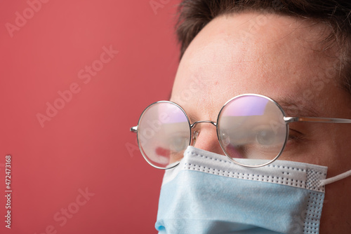 Young man with misted up eyeglasses due to facemask