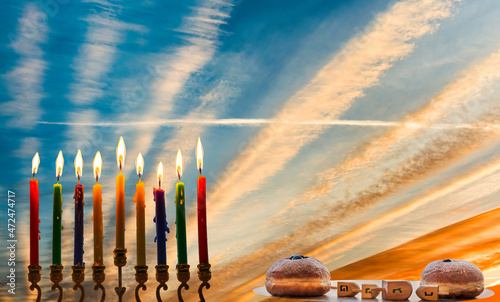 Burning wax candles and sweet donuts with dreidels as symbols of Hanukkah Hol...