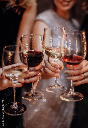 Female hands holding a glasses with dark red and white wine. Celebration, holiday, bachelorette party, birthday concept