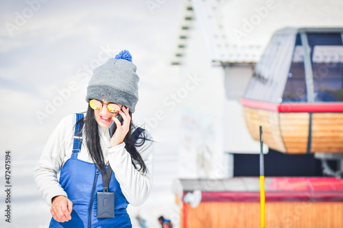 Young female guide instructor on phone call in ski holiday resort outdoors