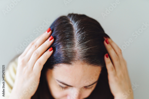 Closeup of woman s head with parted gray hair regrown roots becouse of quarantine. Female show her grey hair. Stress, aging.