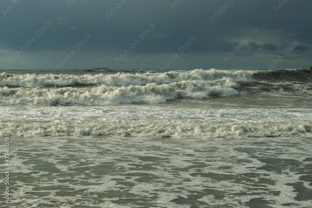 Fototapeta premium foamy sea walls roll onto a deserted shore from a stormy sea