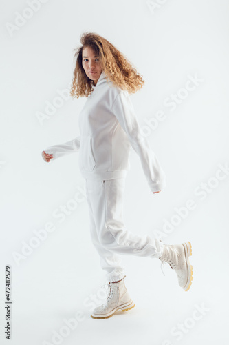 Attractive woman with thick curly hair in a white suit of hoodies and sweatpants.