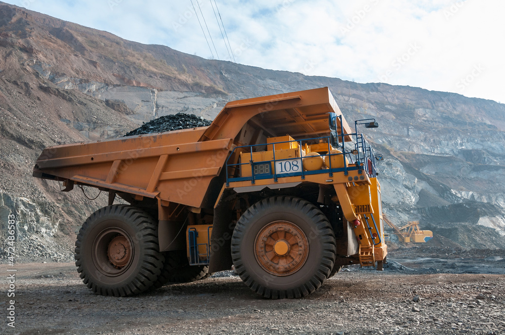 Obraz premium open cast mine dump trucks drive alone industrial area of iron ore quarry