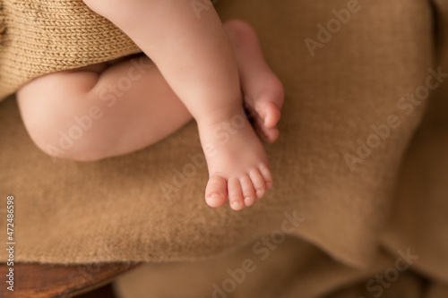 Newborn legs on a brown blanket