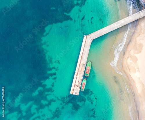 Wooden dock and two boats with blue sea. Aerial drone view of beautiful sea and beach. Summer holiday background view. © Kaan