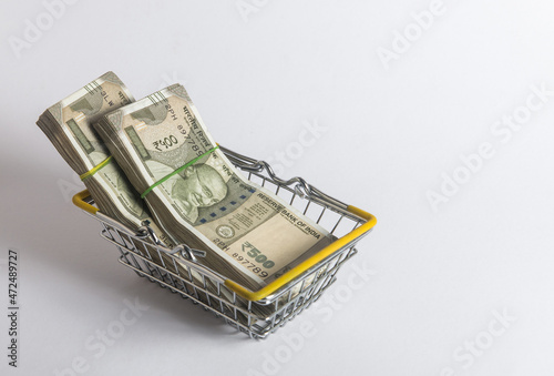 Five hundred Indian rupee currency notes placed in a mini shopping cart. Concept for 'retail banking', 'inflation' or 'financial products'. photo