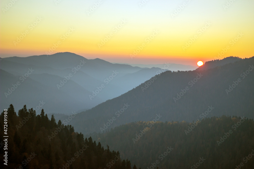 Obraz premium The sun is setting over the mountains.