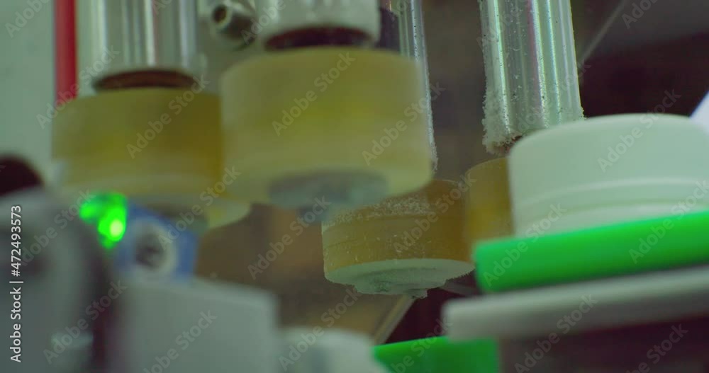 modern pharmaceutical production.a special device fixes the lid on a plastic bottle that moves along the conveyor.technological process close-up. modern pharmaceutical production.a special device fixes the lid on a plastic bottle that moves along the conveyor.technological process close-up.