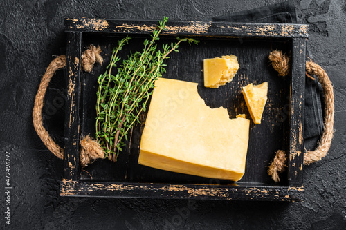 Swiss Hard cheese piece in wooden tray. Black background. Top view