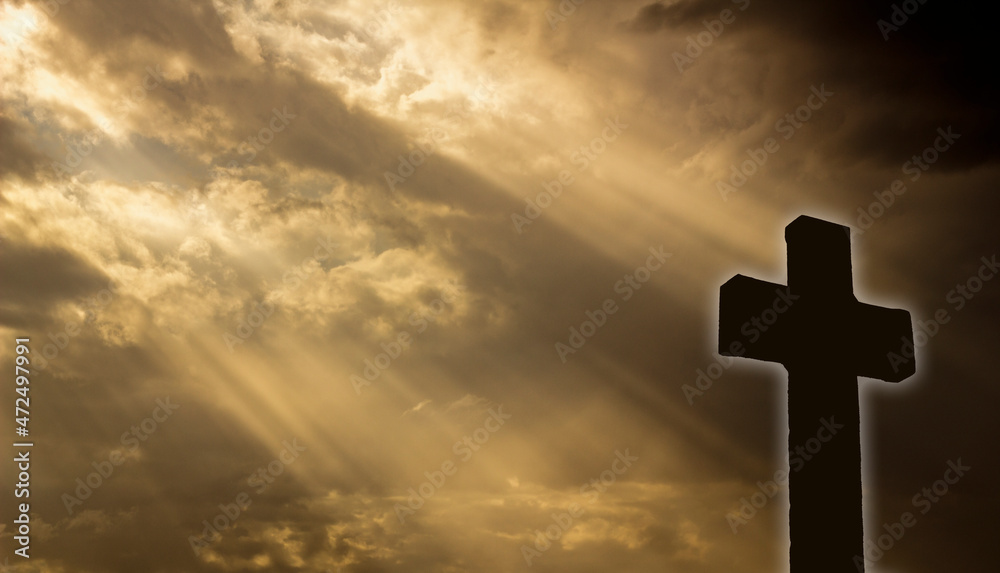 backlighting of a Christian cross glowing with the sun's rays filtered through the clouds at sunset. space copy. text copy