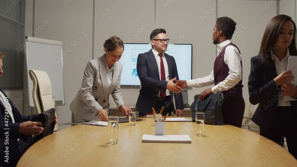 Dolly-out shot of team of businesspeople finishing financial meeting and shaking hands before leaving conference room Dolly-out shot of team of businesspeople finishing financial meeting and shaking hands before leaving conference room