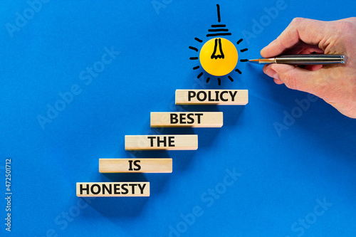 Honesty is the best policy symbol. Wooden blocks with words Honesty is the best policy on blue background, copy space. Light bulb icon. Businessman hand, pen. Business, honesty best policy concept.