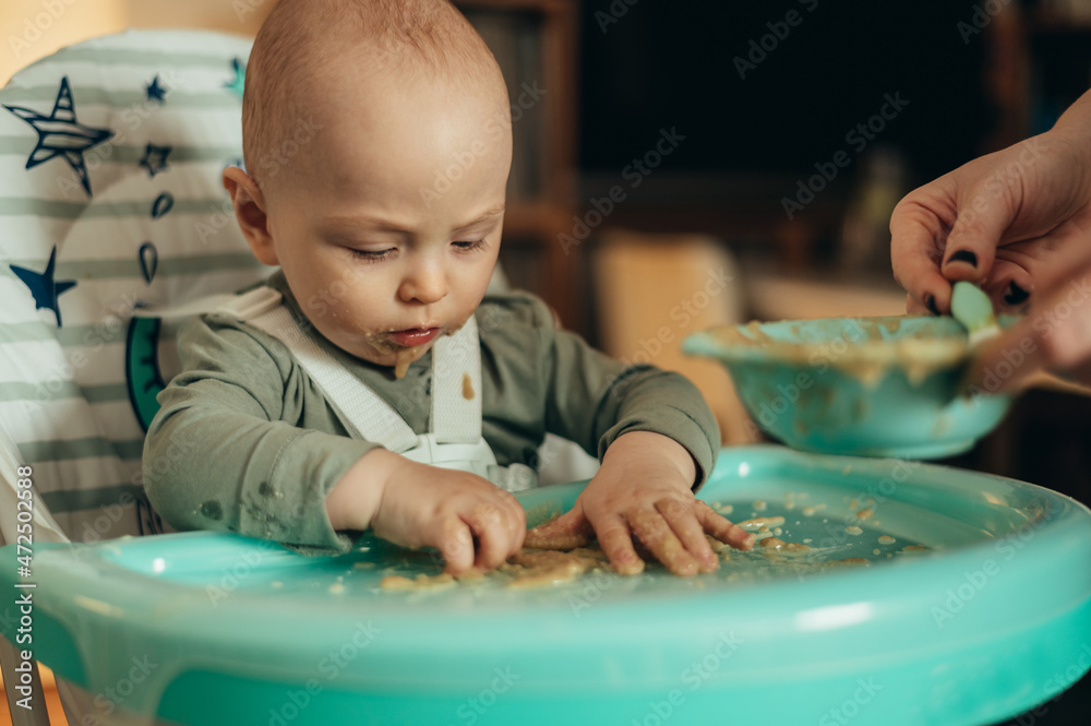 Baby eating with a face stained in food while in a child's dining chair Baby eating with a face stained in food while in a child's dining chair