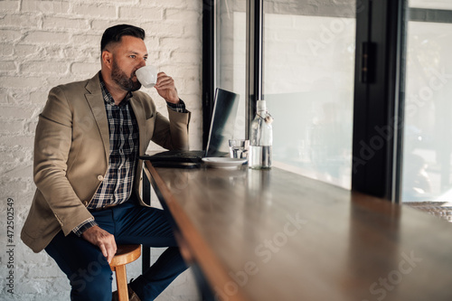 Businessman working on his laptop while drinking coffee in a cafe